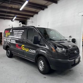 Custom commercial vehicle wrap on a black service van with branded graphics and contact details