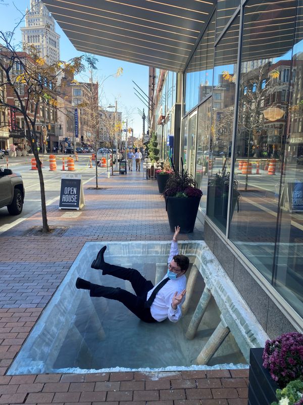 Masked man seated on public sidewalk in pedestrian-friendly space