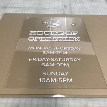 etched glass sign that reads hours and operation