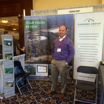 man standing in front of timmons group trade show display