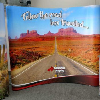 Speedpro imaging follow the road less traveled marketing display with desert road and cactus images 