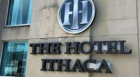 Outdoor signage for The Hotel Ithaca featuring the company logo on the building wall