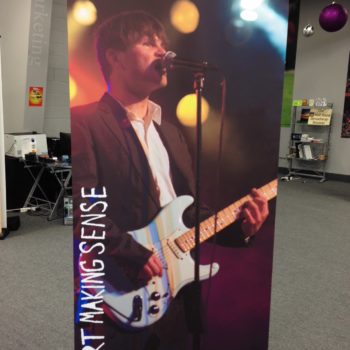 Standing banner with man singing and playing guitar with phrase start making sense