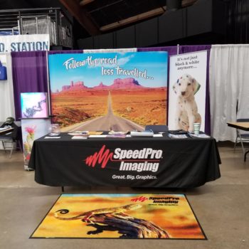 SpeedPro Imaging tradeshow display with follow the road less travelled background
