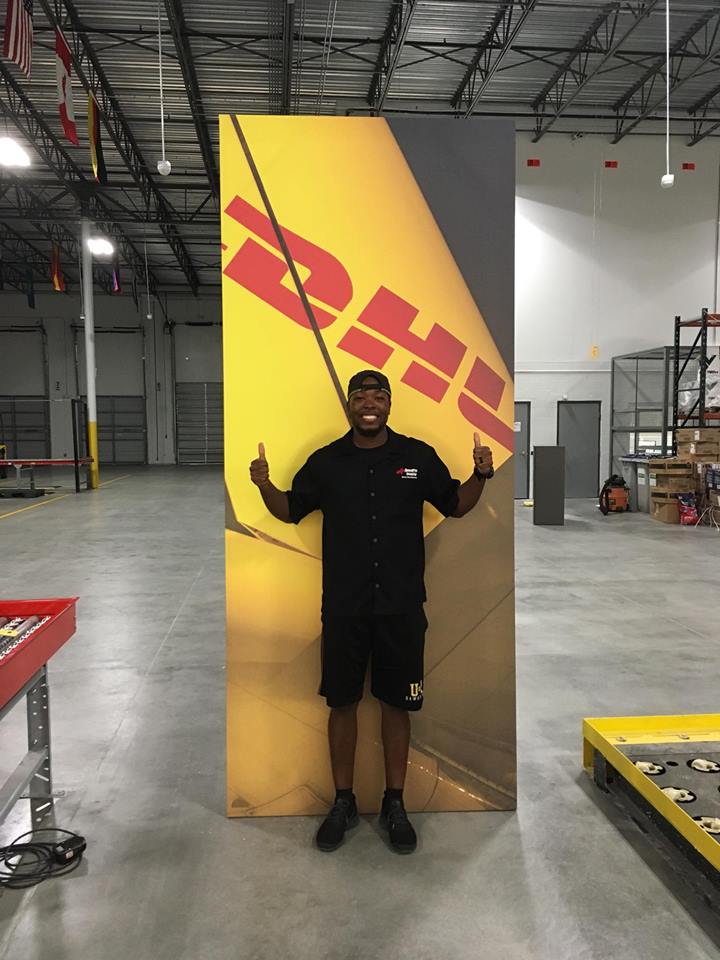 man standing in front of DHL banner with two thumbs up