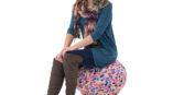 woman wearing blue shirt, scarf, and brown boots sitting on covered exercise ball seat