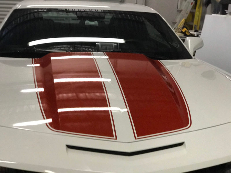 white camaro with 2 red stripes on hood of car