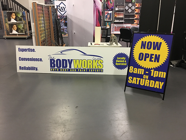 banner and a frame sign for The Body Works Auto Body and Paint Experts