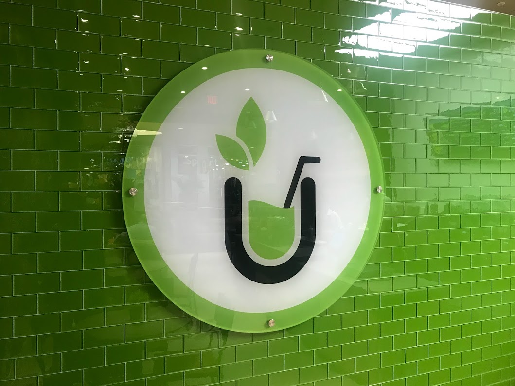 circular indoor signage with green leaf against green tile background