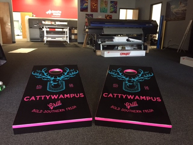 two corn hole boards with text Cattywampus grill