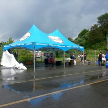 blue event tent on parking lot with people walking around