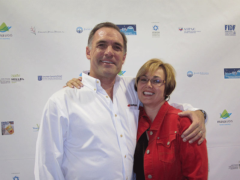 couple posing in front of step and repeat wall
