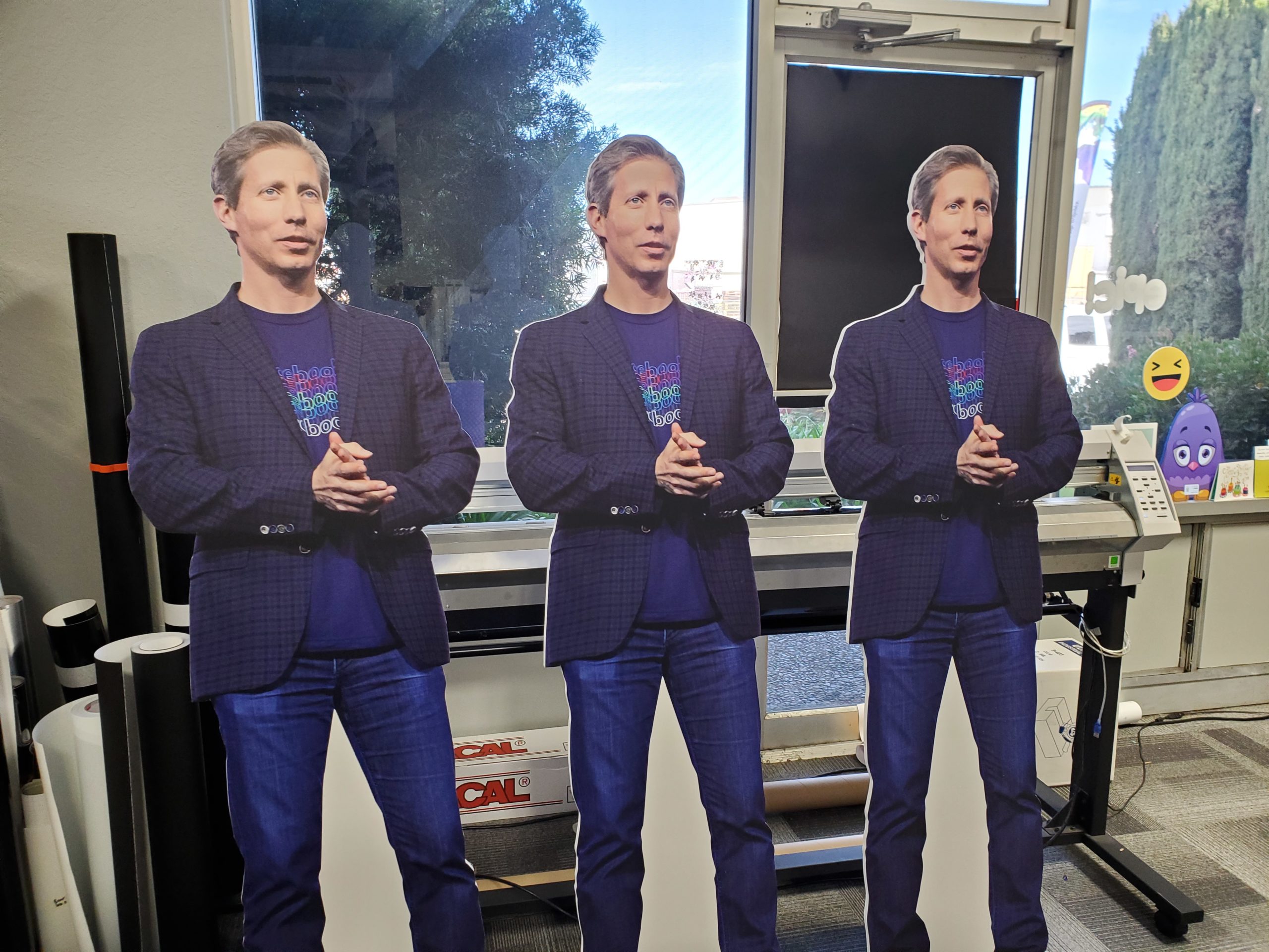 three standing cardboard cutouts of the same man