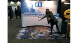 woman standing over ifti trade show display sharks on ground 