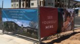 Colorful imagery and text on fence banners in front of an assisted living construction site