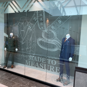 the front of a suit shop/tailor that with a mural that says "made to measure"