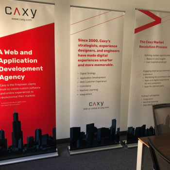three large retractable banners with information and branding for "Caxy"