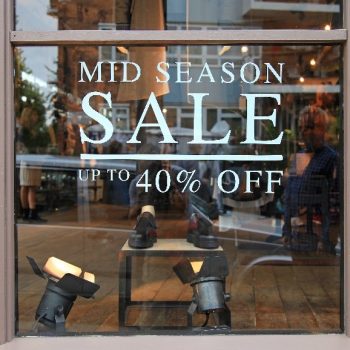 vinyl lettering on a window that says "Mid Season Sale Up To 40% Off"