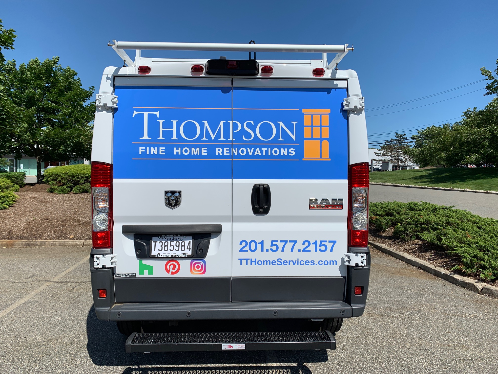 Back of white van with blue wrap that says Thompson Fine Home Renovations in white with an outline of a building in orange.