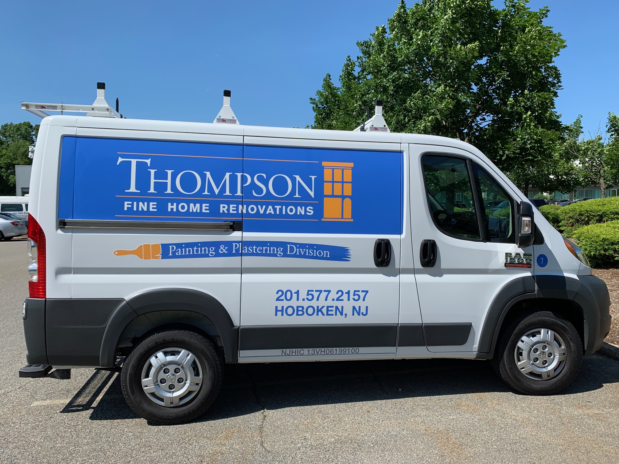 Side of white van with blue wrap that says Thompson Fine Home Renovations in white with an outline of a building in orange.