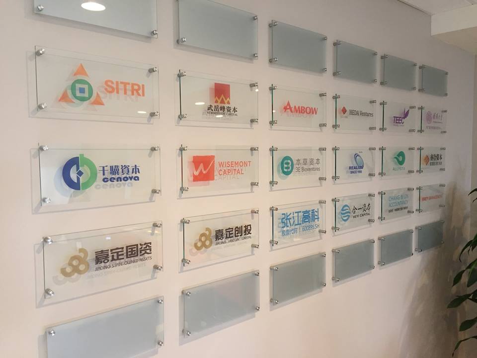 White wall with glass plates that have various company logos on them.