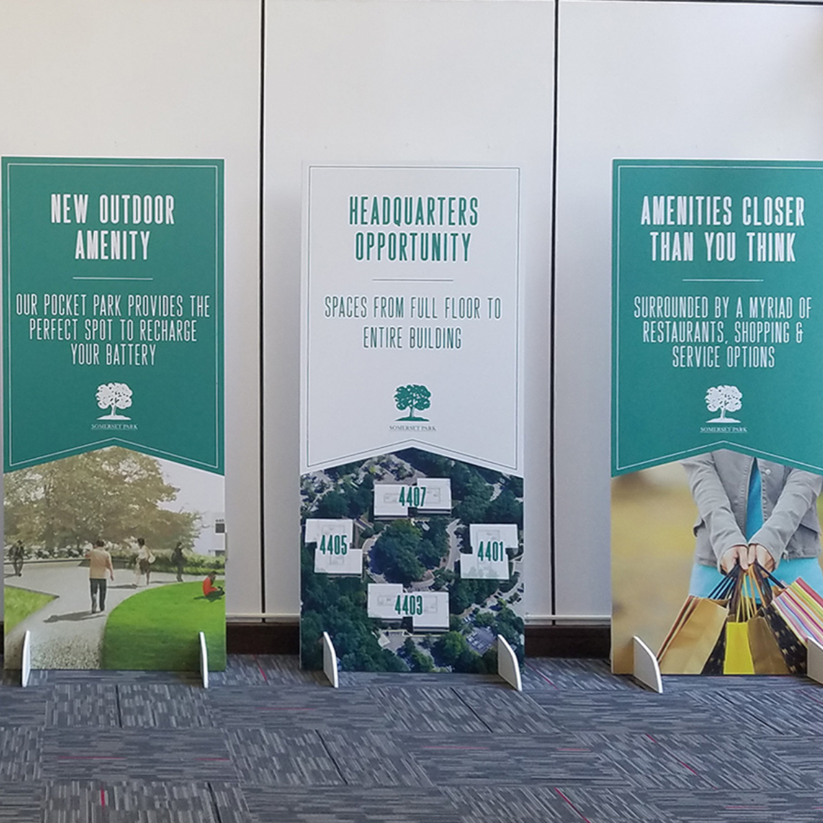 Event display banners promoting new outdoor amenities and headquarters opportunities, featuring green and white graphics.