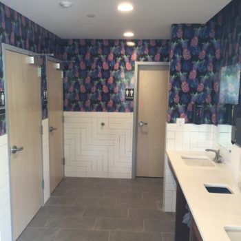 Bathroom with sinks, tile floor, and pineapple wallpaper 