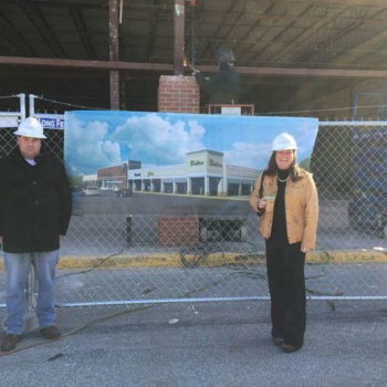 Man and woman in hard hats standing in front of banner