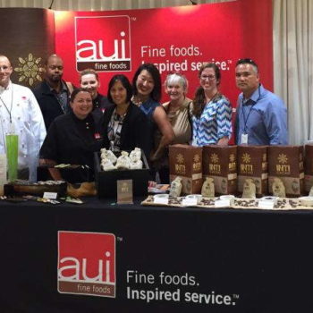 AUI fine foods employees with printed banner and tablecloth