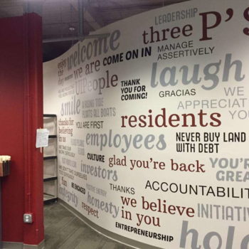 White wall mural with black gray and maroon lettering
