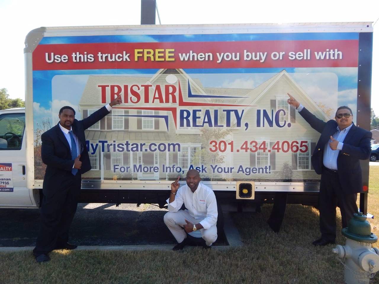 Three men posing with tri star reality trailer wrap 