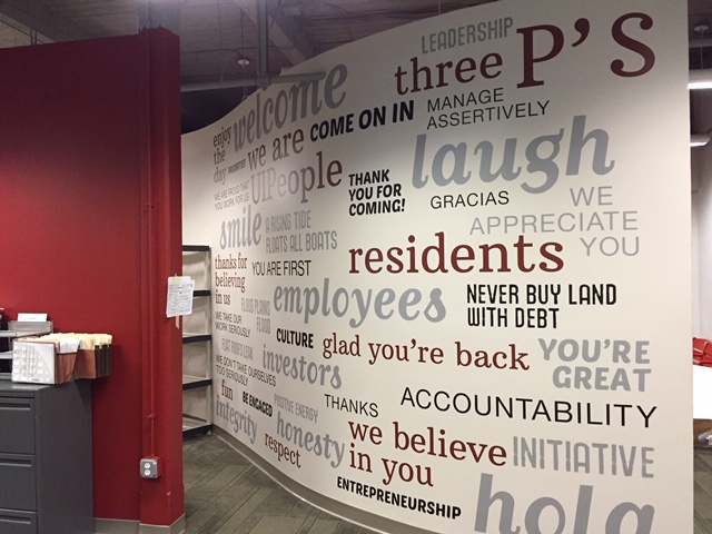 White wall with maroon and grey printed word graphics 