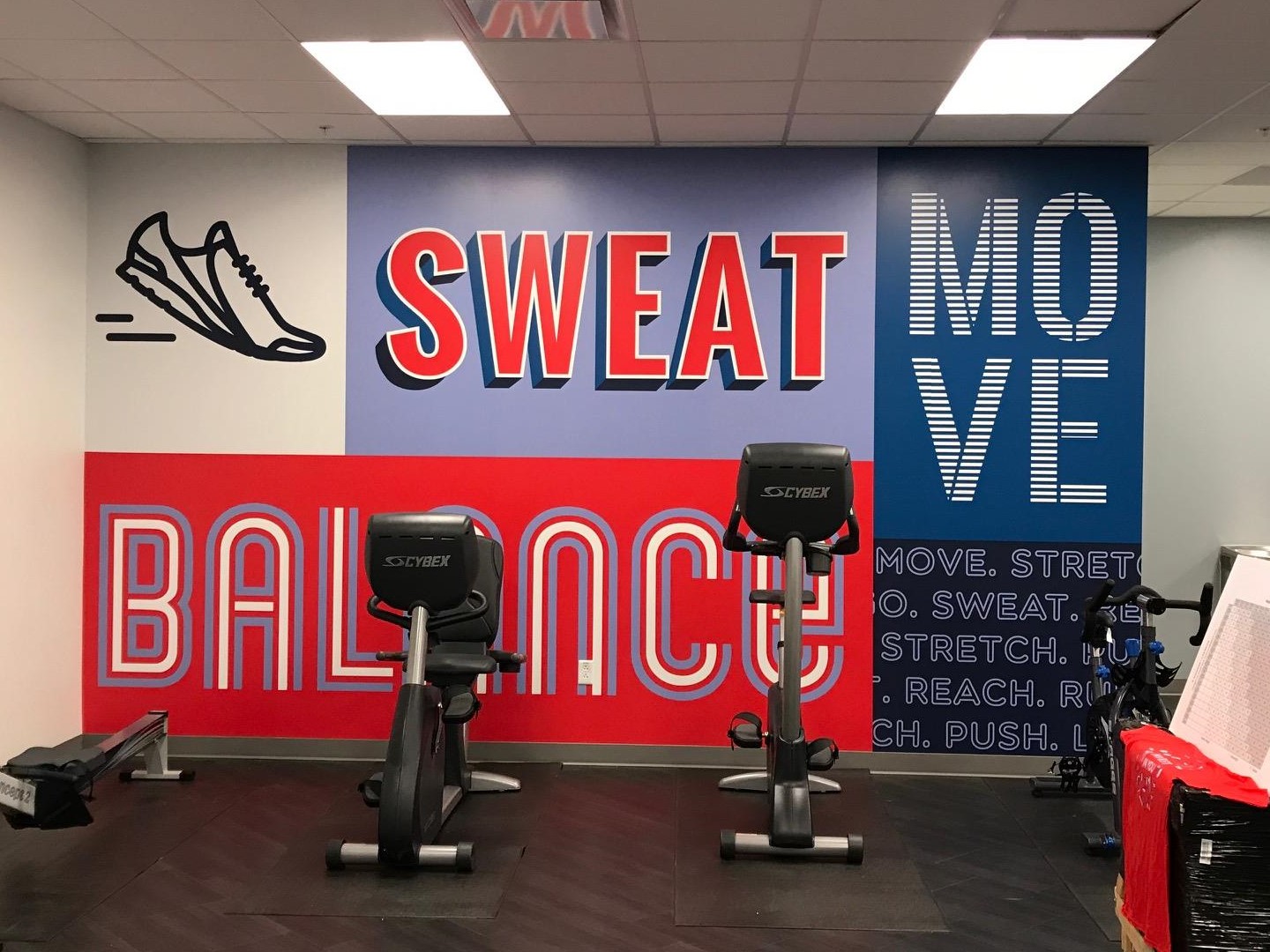 Gym wall with motivational words and exercise bikes in front.