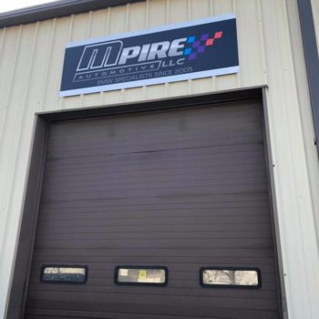 Outdoor sign for MPire Automotive LLC featured above their garage door 