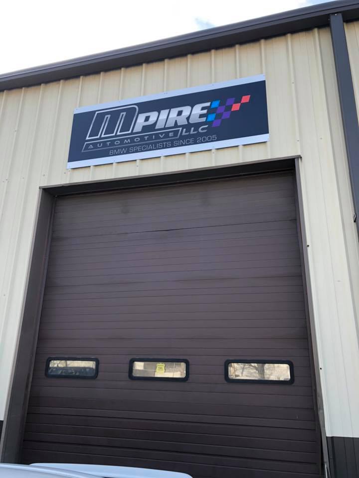 Outdoor sign for MPire Automotive LLC featured above their garage door 