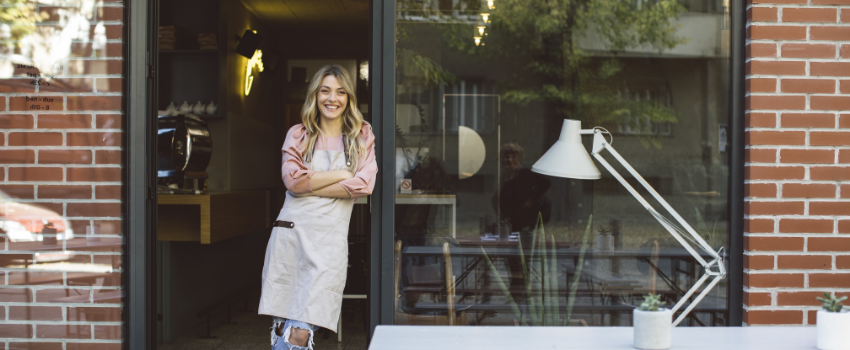 Woman wearing an apron leaning against a brick wall