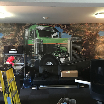 wall graphic of a green truck breaking a brick wall