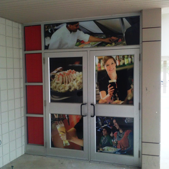 Window graphics showing cooks and bar tenders on the front doors to a local restaurant.