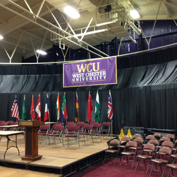 A West Chester University banner hanging over a stage during a college graduation ceremony.