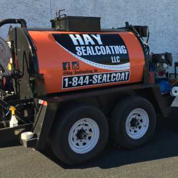 A specialty trailer with a custom designed vehicle wrap for Hay Sealcoating LLC.