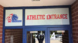 Athletic entrance signage with 'ATHLETIC ENTRANCE' text and Hill Trailblazers logo on glass door.