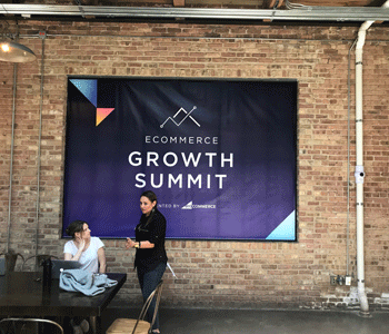 A graphic hanging on a wall advertising the eCommerce Growth Summit.