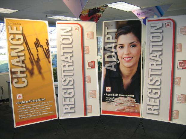 Retractable banner displays featuring the topics 'Change,' 'Registration,' and 'Adapt' with a professional woman’s portrait.