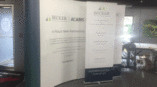 Retractable display banners for Becker Professional Education showcasing project management training information.