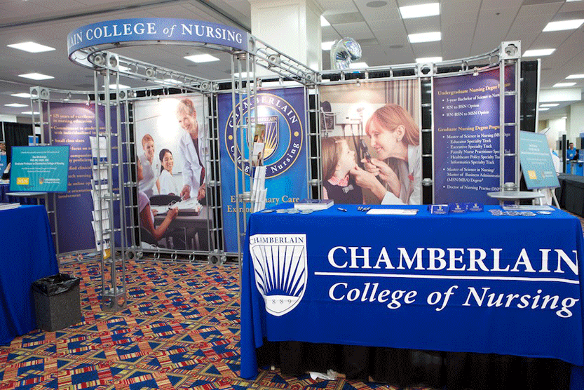 Trade show display for Chamberlain College of Nursing featuring branded table cover and informational banners.