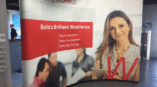 Curved trade show backdrop for DeVryWORKS featuring the tagline 'Build a Brilliant Workforce' alongside service details.