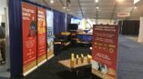 Trade show booth display featuring retractable banners with red and yellow graphics, showcasing ECOFAB products and services.