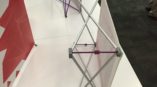 Retractable banner stand with graphic display showcasing a geometric red design in an indoor setting.