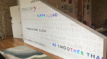 Environmental wall graphics for Dermaflash, featuring inspirational phrases and branded logo on white wall surface.