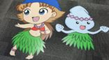 Cutout standees of a dancing girl in a grass skirt and a smiling character with a flower crown on a carpeted floor.